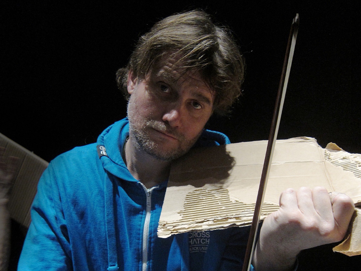 Picture of Dom Elias a.k.a. Dominik Elias Schlienger pretending to play viola on a piece of ripped cardboard